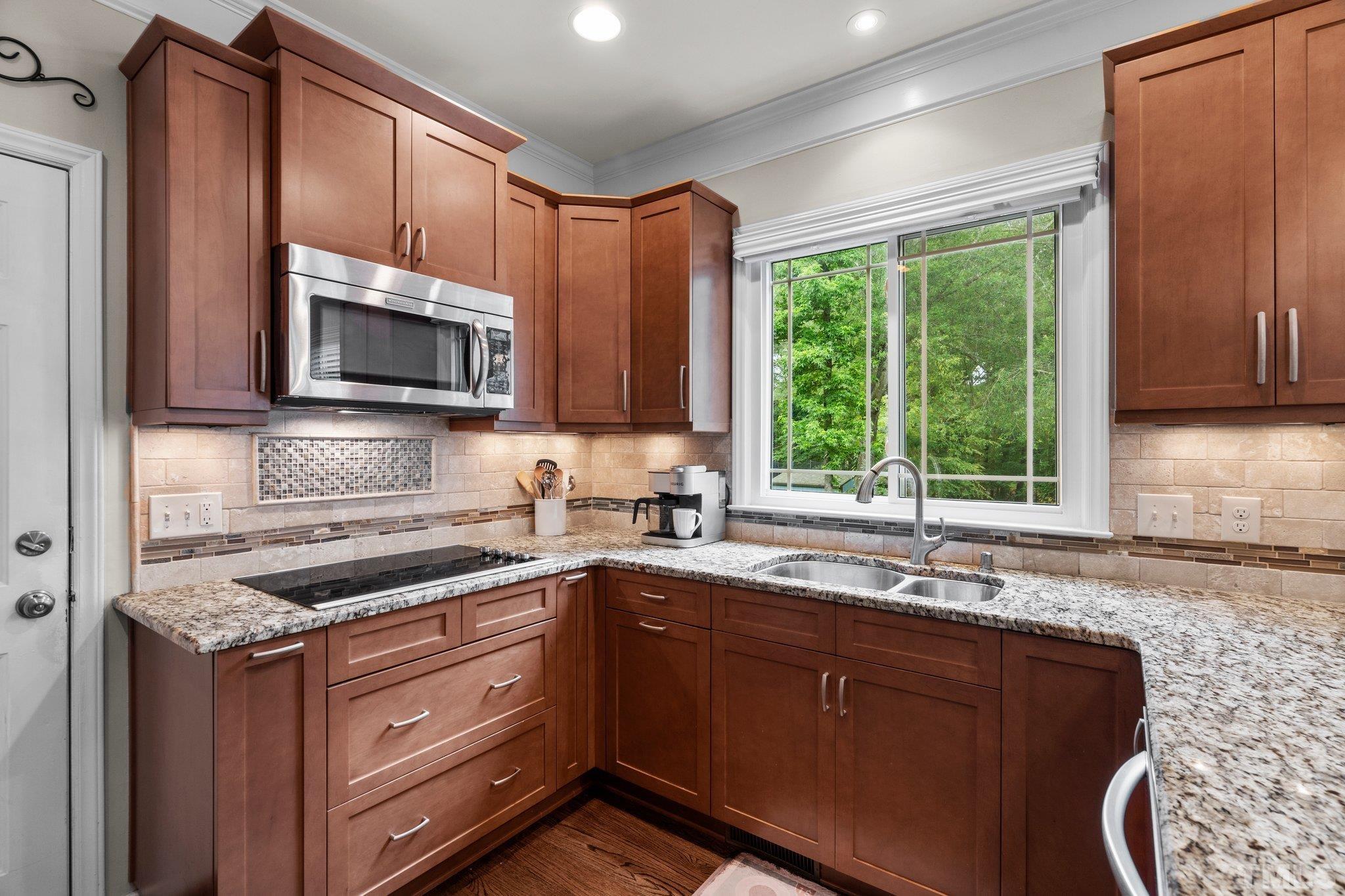 102 Sequoia Court Cary, NC 27513 - Photo 16 of 36 a kitchen with granite countertop wooden cabinets a sink a window and stainless steel appliances