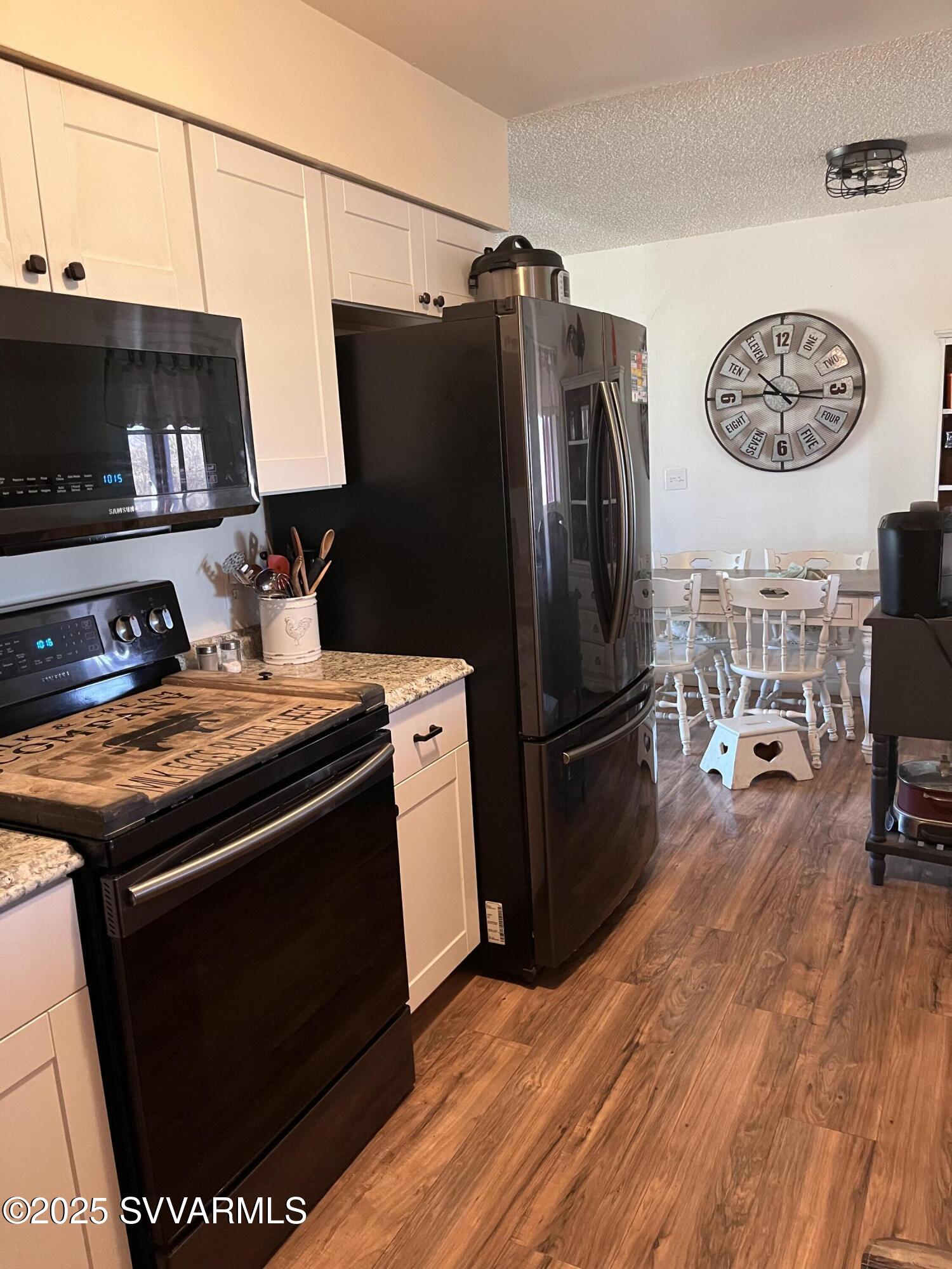 3405 South Silver Road Camp Verde, AZ 86322 - Photo 10 of 56 a kitchen with stainless steel appliances granite countertop a stove top oven a refrigerator a dining table and chairs with the wooden floor
