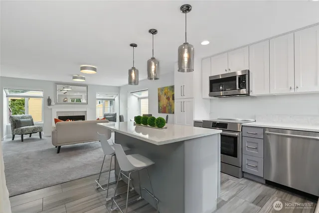 a kitchen with stainless steel appliances granite countertop a stove top oven a sink dishwasher a dining table and chairs with wooden floor