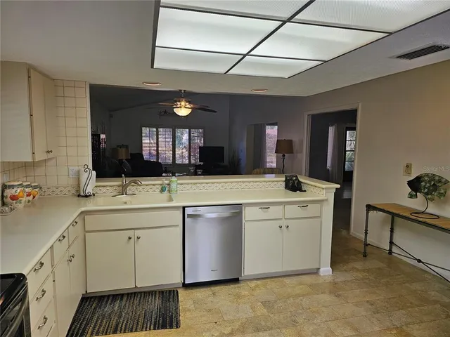 a large kitchen with a sink and dishwasher a stove with wooden floor