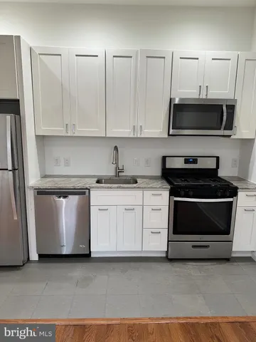 a kitchen with granite countertop white cabinets and stainless steel appliances