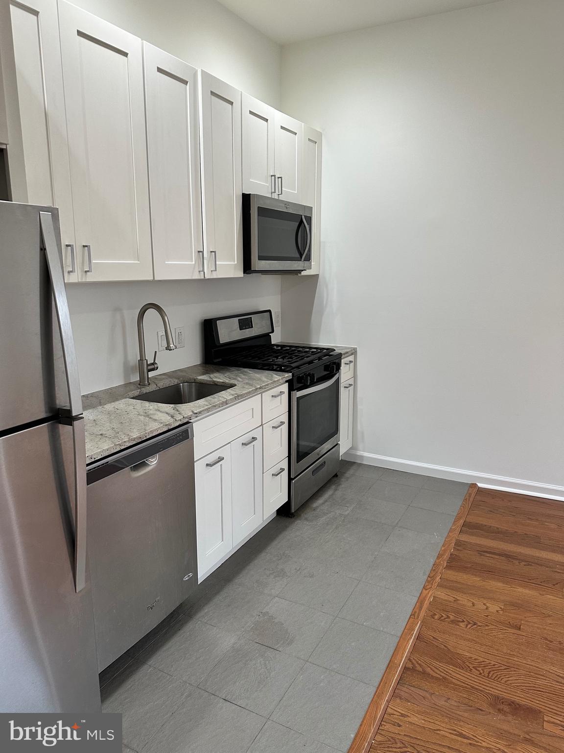 1128 South 19th Street, Unit A Philadelphia, PA 19146 - Photo 5 of 17 a kitchen with stainless steel appliances granite countertop a stove a sink and a microwave