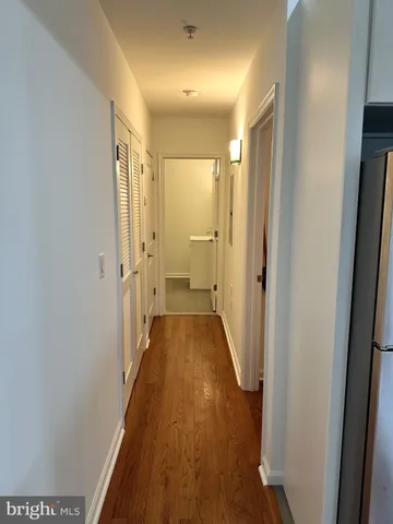 a view of a hallway with wooden floor and a bathroom