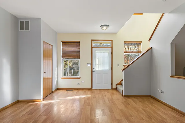 a view of an empty room with wooden floor and stairs