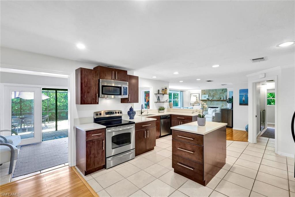 237 Burning Tree Drive Naples, FL 34105 - Photo 5 of 26 a kitchen with stainless steel appliances granite countertop a stove top oven a sink dishwasher a dining table and chairs with wooden floor