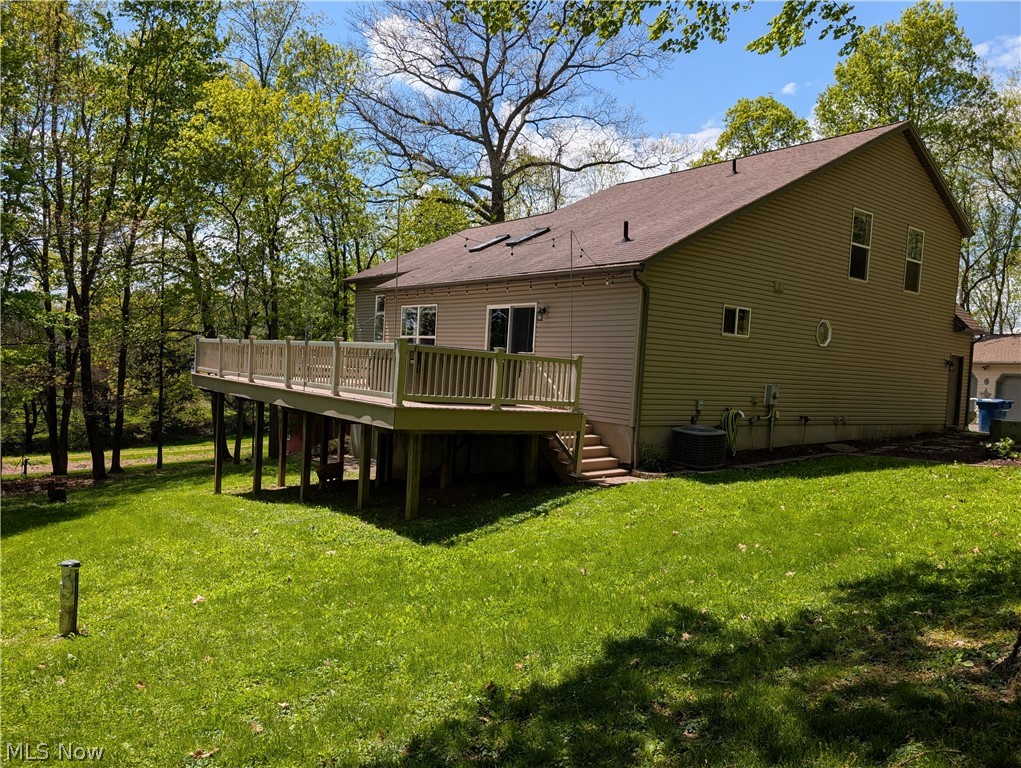 11154 Johnsford Road Southwest Beach City, OH 44608 - Photo 5 of 50 Spacious elevated deck with light-toned railings and steps, set against a backdrop of mature trees