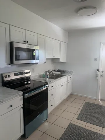 a kitchen with granite countertop a stove a microwave and white cabinets