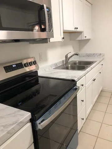 a kitchen with granite countertop a sink stove and cabinets