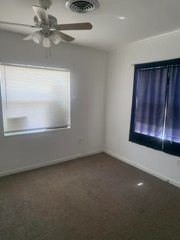 an empty room with windows and fan