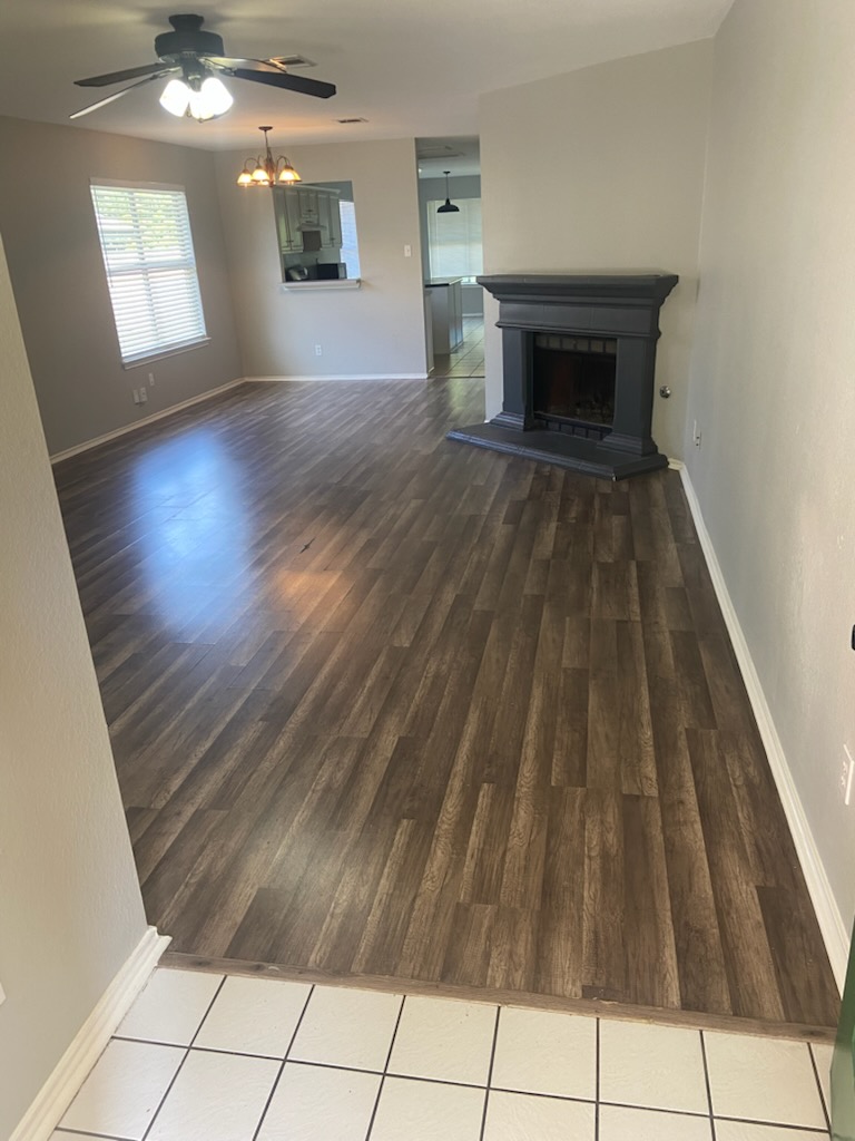 17616 Tobermory Drive Pflugerville, TX 78660 - Photo 3 of 14 A welcoming living space features warm plank flooring, an inviting fireplace, and a convenient kitchen pass-through.