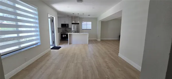 a view of a kitchen with refrigerator and wooden floor