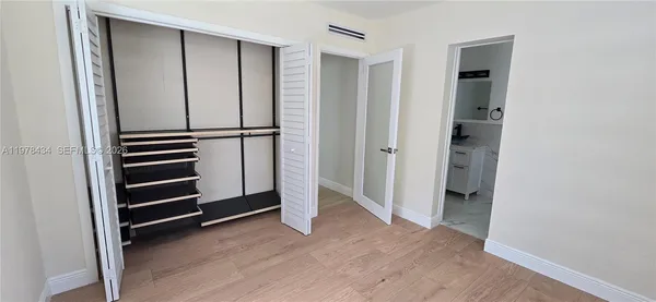an empty room with wooden floor closet and windows