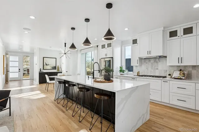 a kitchen with stainless steel appliances granite countertop a sink a stove and chairs