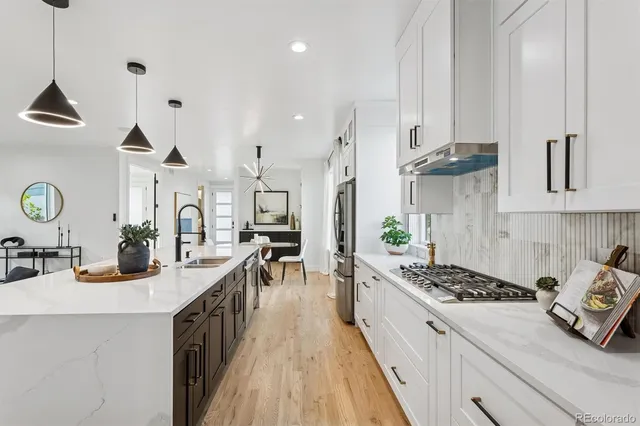 a kitchen with stainless steel appliances kitchen island wooden cabinets a stove a sink a dining table and chairs