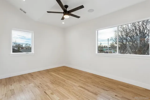 a view of empty room with wooden floor and fan