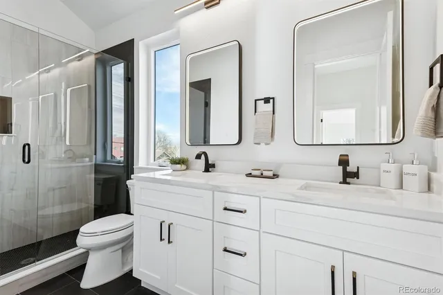 a bathroom with a double vanity sink toilet mirror and shower