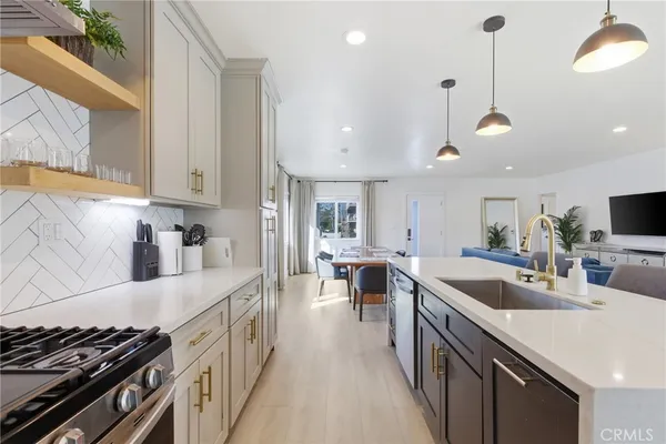 a kitchen with stainless steel appliances a sink a stove a refrigerator cabinets and wooden floor