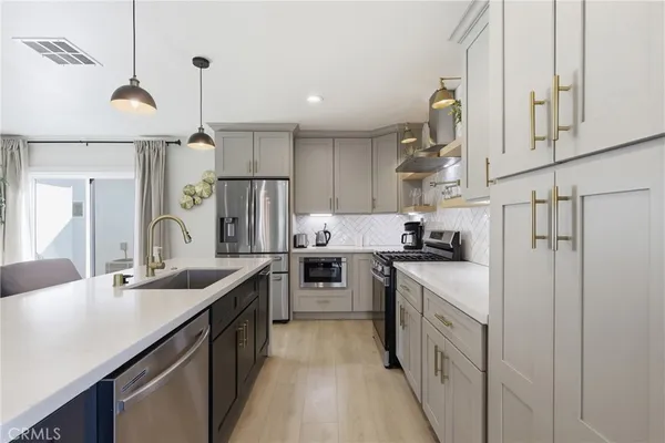 a kitchen with stainless steel appliances granite countertop a sink a stove a refrigerator and island with wooden floor