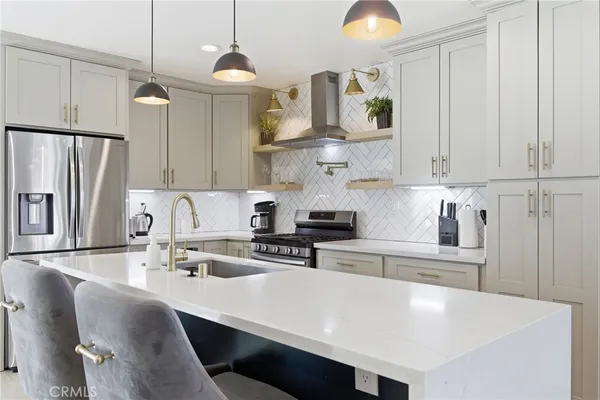 a large kitchen with stainless steel appliances kitchen island a large counter top and a refrigerator