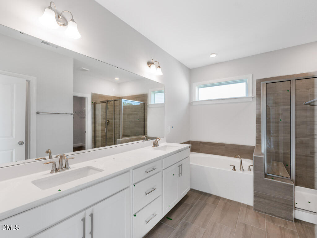 348 Canyon Gap Way Raleigh, NC 27610 - Photo 28 of 33 a bathroom with a double vanity sink a mirror and a bathtub