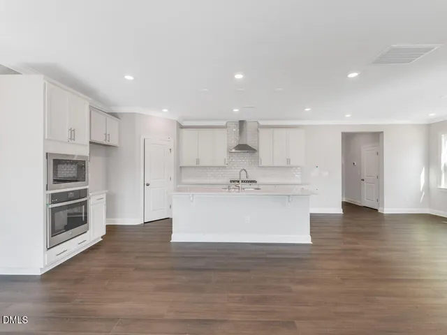 a view of an empty room with a window and a kitchen