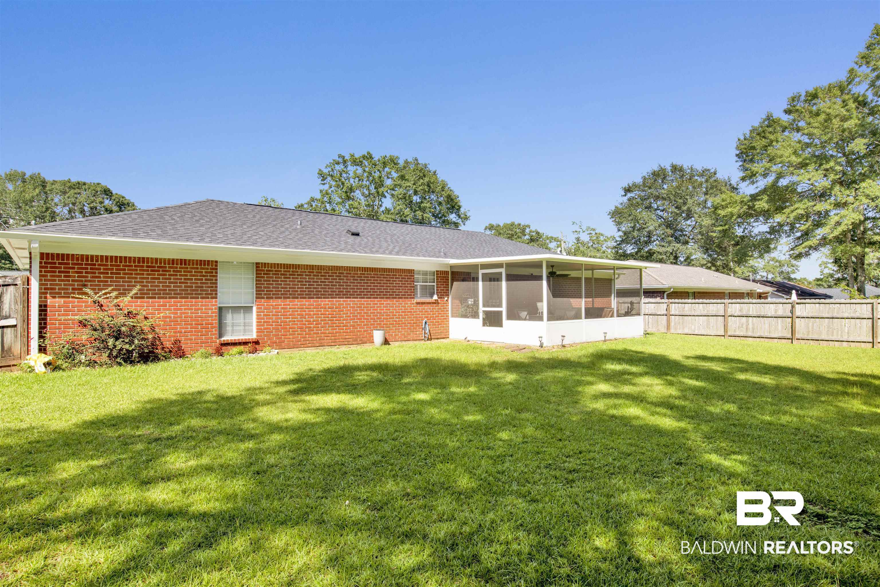 6281 Woodside Drive Theodore, AL 36582 - Photo 16 of 17 Rear view of house featuring a sunroom, a fenced backyard, roof with shingles, and brick siding
