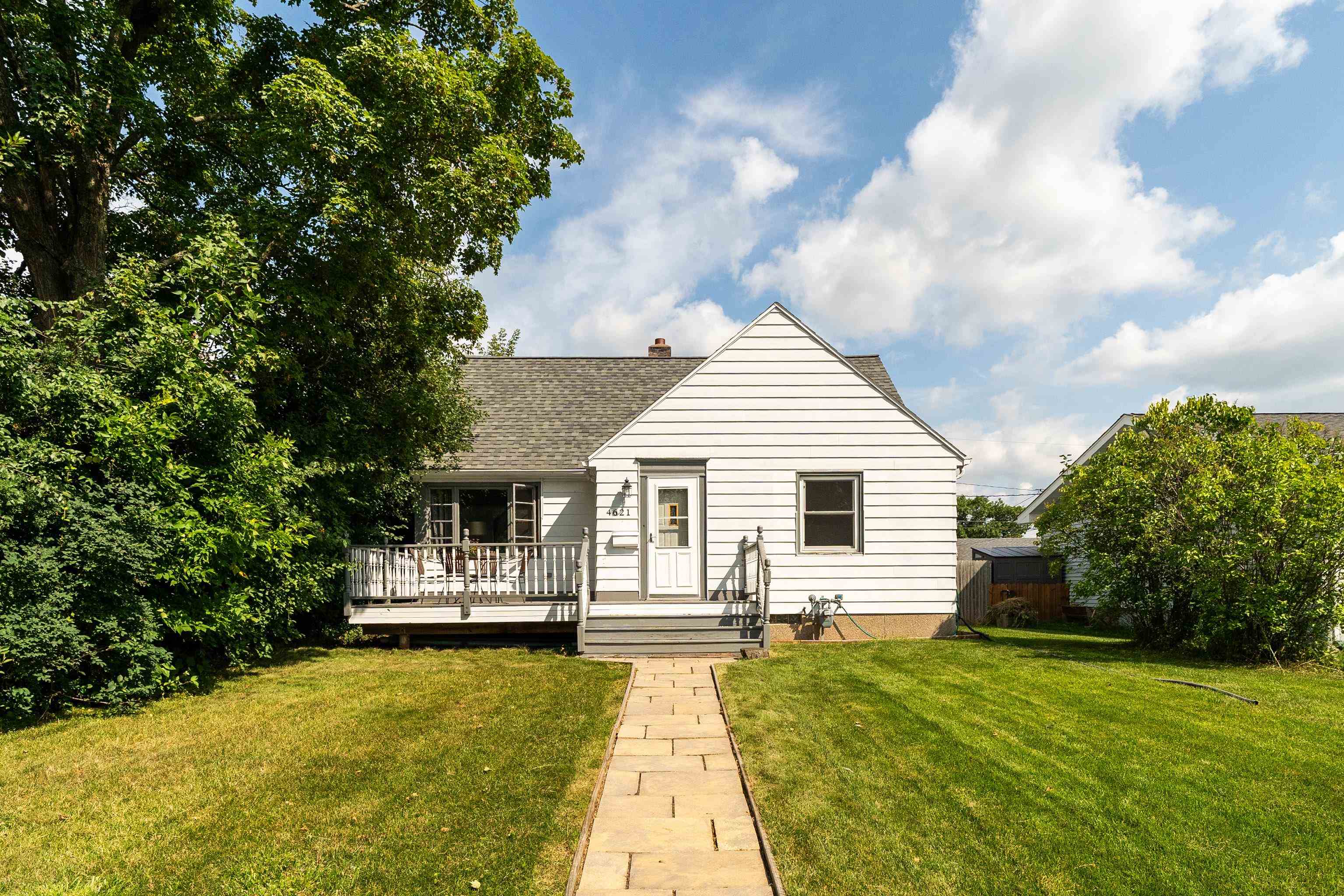 View of front of property featuring a front lawn, a deck, roof with shingles, and a chimney