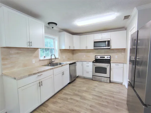 a kitchen with sink a microwave and cabinets