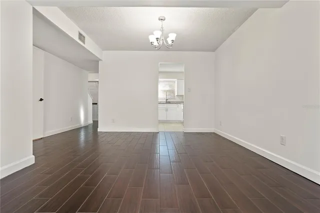 a view of an empty room with wooden floor and a chandelier