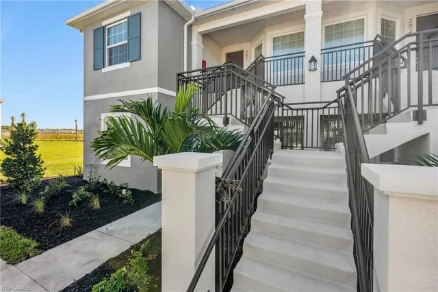 a view of a house with large windows and flower plants