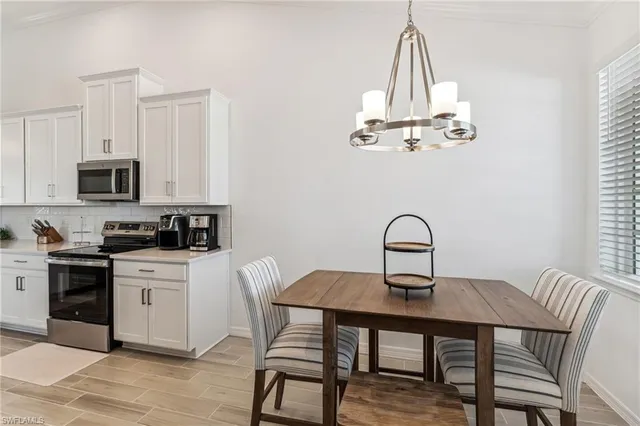 a kitchen with a table chairs a stove and white cabinets