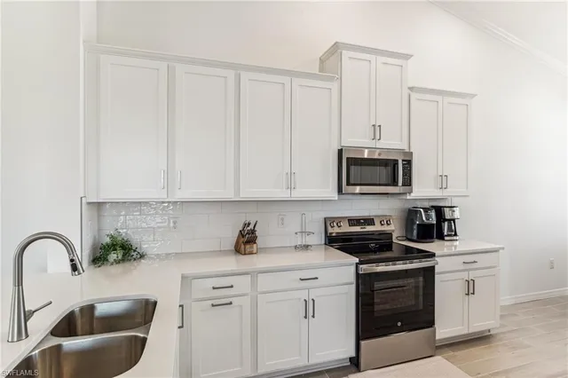a kitchen with stainless steel appliances granite countertop white cabinets a stove a sink and dishwasher