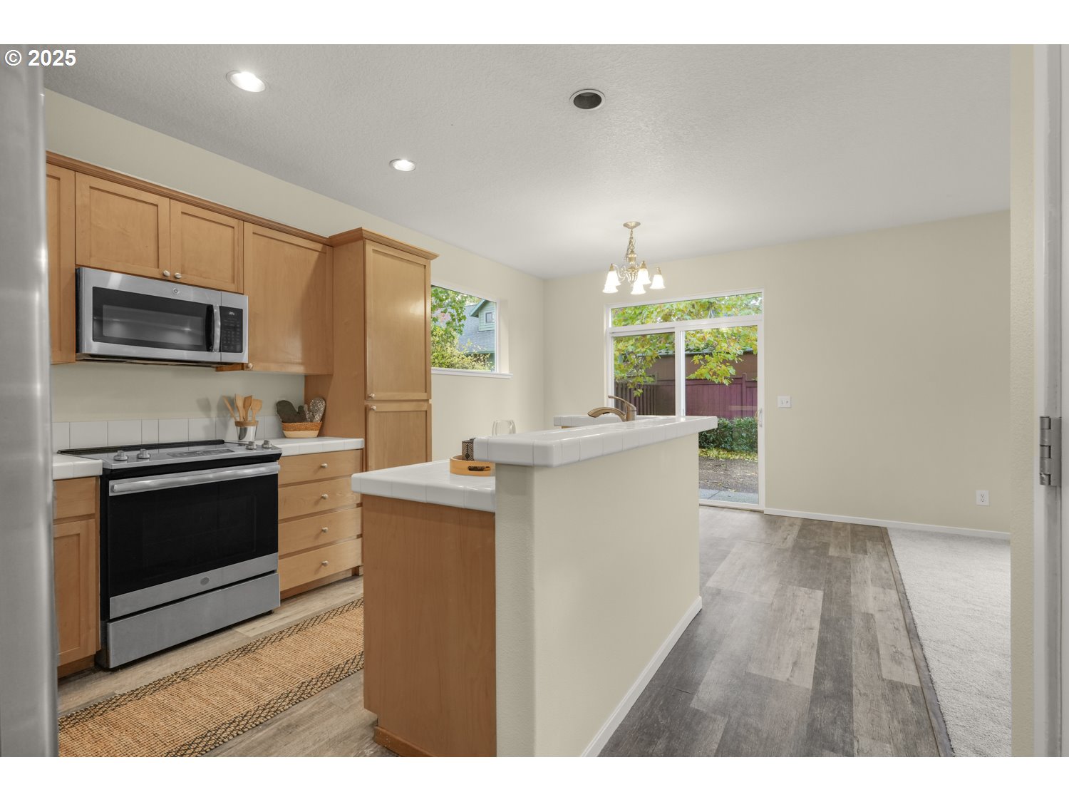 20591 Southwest Ravenswood Street Beaverton, OR 97078 - Photo 11 of 31 a kitchen with kitchen island granite countertop a stove top oven a sink dishwasher a dining table and chairs with wooden floor