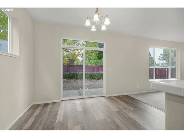 a view of an empty room with wooden floor and fan