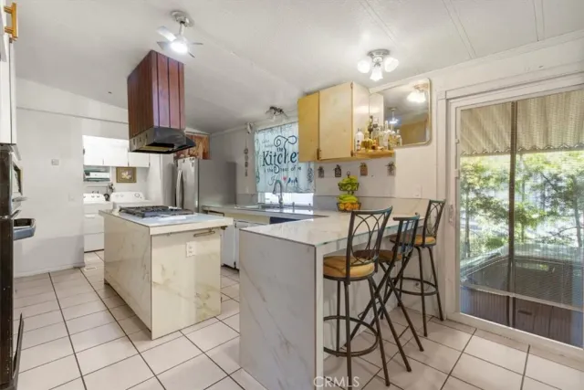 a kitchen with stainless steel appliances kitchen island granite countertop a stove a sink and a dining table