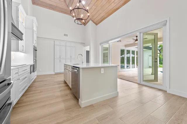 a large kitchen with stainless steel appliances a large counter top and a chandelier