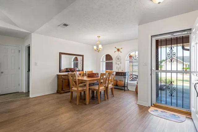 a view of a dining room with furniture a chandelier and wooden floor