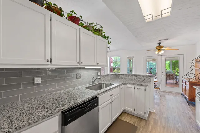 a kitchen with stainless steel appliances granite countertop a stove top oven a sink dishwasher and a refrigerator with wooden floor