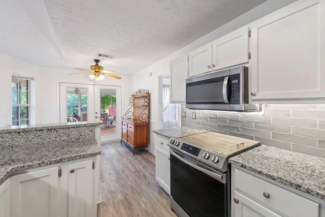 a kitchen with stainless steel appliances granite countertop a kitchen island a stove a dining table and chairs with wooden floor