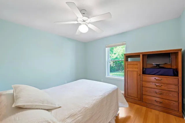 an empty room with wooden floor fan and windows