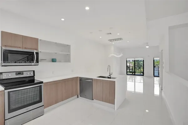 a large white kitchen with granite countertop a stove a sink and a large window