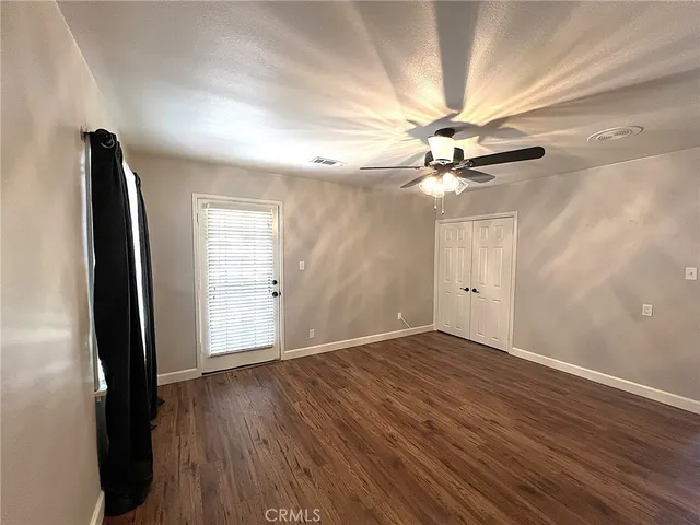 a view of an empty room with window and wooden floor