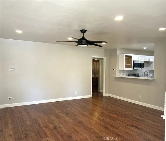 a view of an empty room with a window and wooden floor
