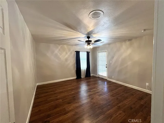 an empty room with wooden floor fan and windows