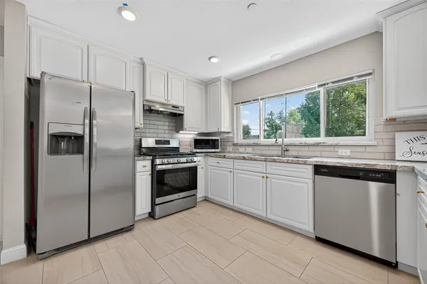 a kitchen with granite countertop a refrigerator sink and stainless steel appliances