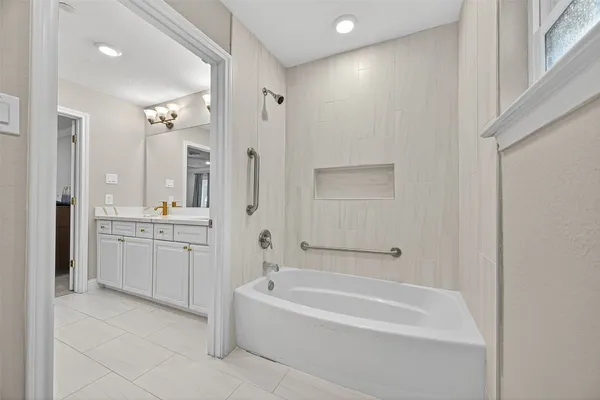a bathroom with a granite countertop sink a mirror a bathtub and shower