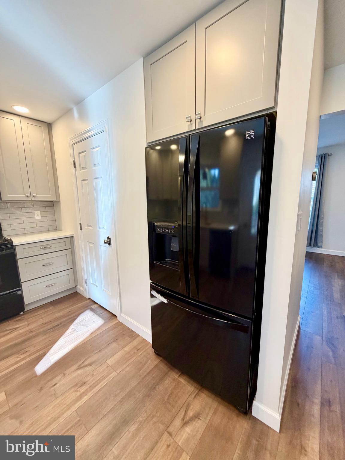 112 Chukar Court Lititz, PA 17543 - Photo 13 of 44 a view of a refrigerator in kitchen and an empty room with wooden floor