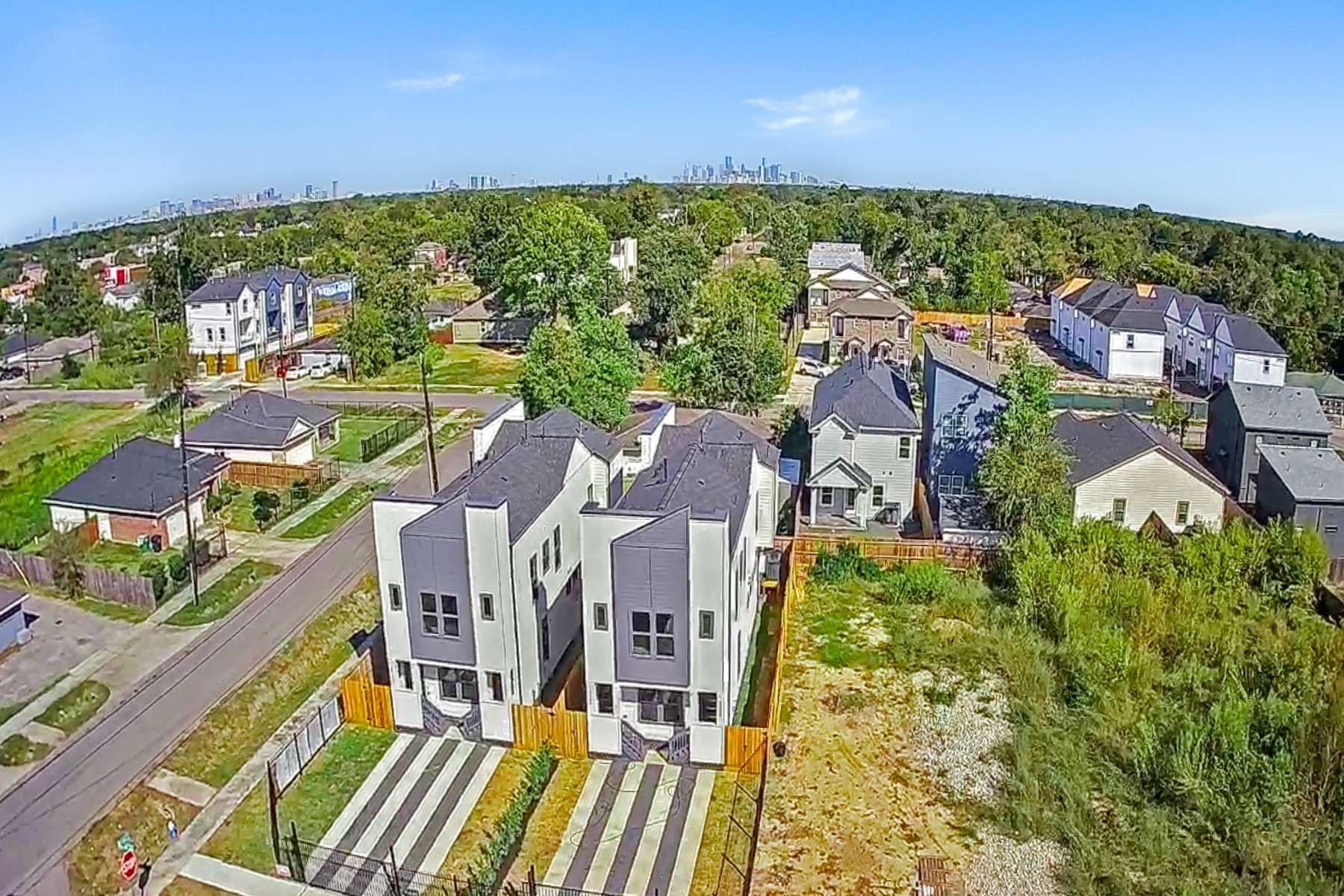 4803 Paula Street Houston, TX 77033 - Photo 28 of 28 This aerial photo showcases modern, multi-story homes in a suburban neighborhood, surrounded by greenery and nearby houses. The area is spacious and well-maintained, with a view of the city skyline in the distance, providing a blend of urban and suburban living.