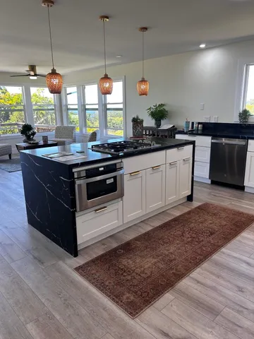 a kitchen with stainless steel appliances granite countertop a stove a sink and a wooden floor