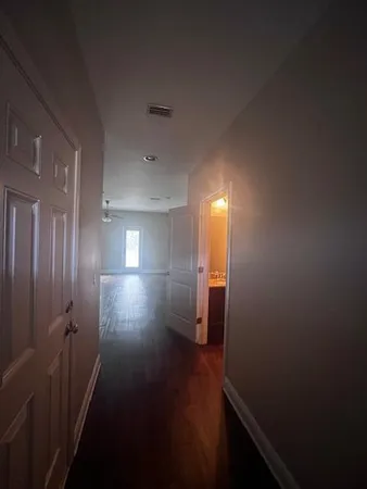 an empty room with wooden floor fan and windows